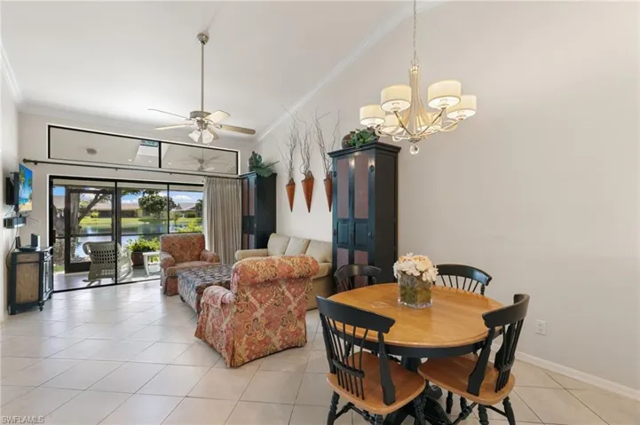 Dining space featuring crown molding, light tile patterned flooring, ceiling fan, and a chandelier
