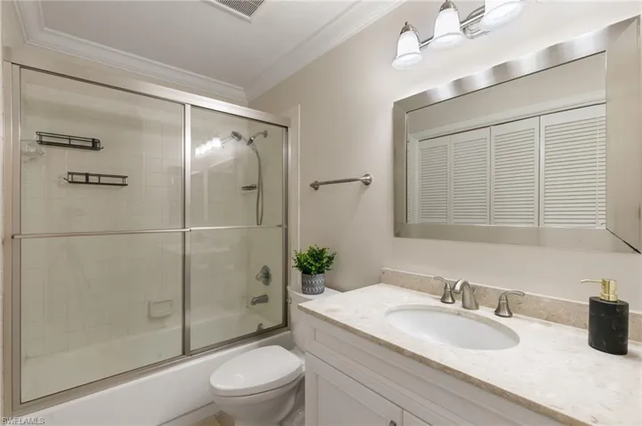 Bathroom featuring vanity, crown molding, and enclosed tub / shower combo