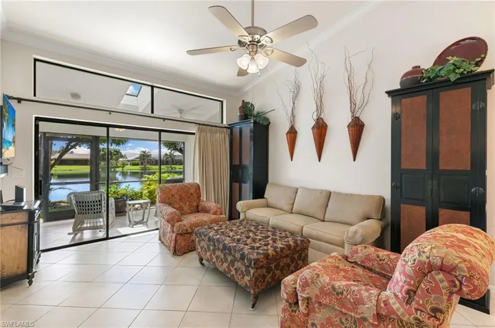 Living area featuring crown molding, light tile patterned floors, a ceiling fan, a water view, and a skylight