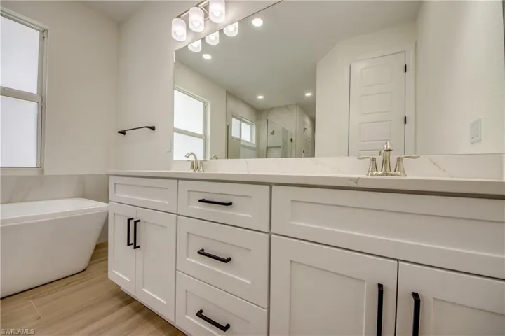 Bathroom featuring wood-type flooring, vanity, and shower with separate bathtub