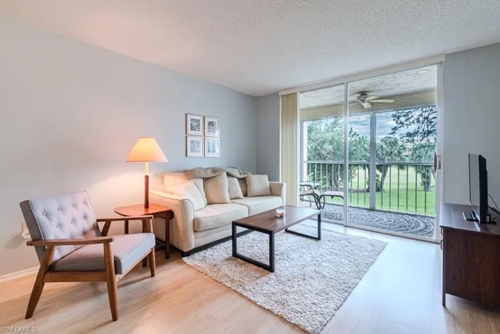 Living room with ceiling fan, light hardwood / wood-style floors, and a textured ceiling