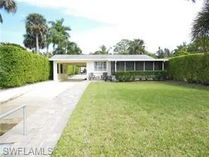 View of front of house with concrete driveway, a carport, a front lawn, and a sunroom