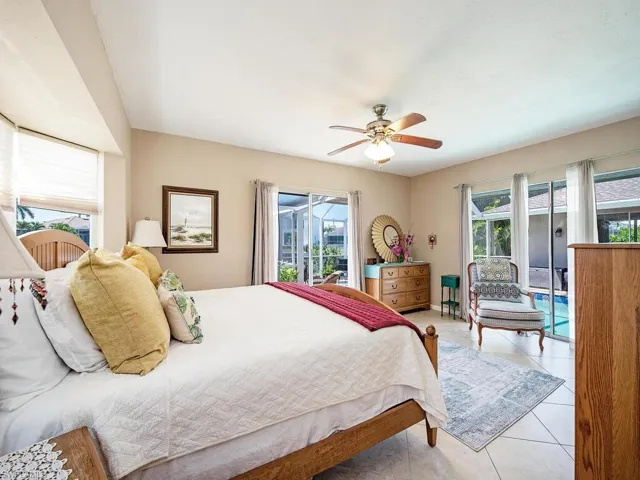 Tiled bedroom with ceiling fan, multiple windows, and access to outside