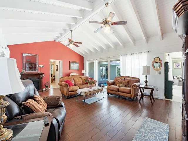Living room featuring lofted ceiling with beams, ceiling fan, and dark hardwood / wood-style flooring