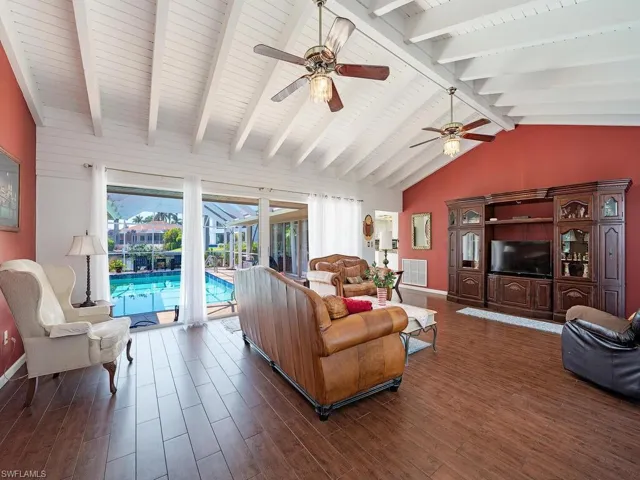 Living room with ceiling fan, lofted ceiling with beams, and dark wood-type flooring