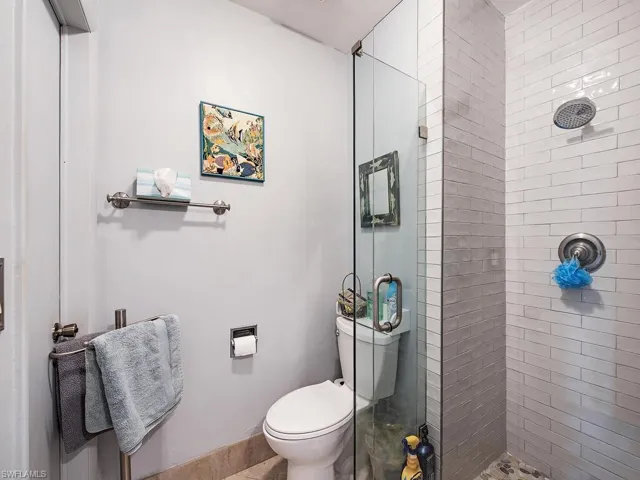 Bathroom featuring tiled shower and toilet