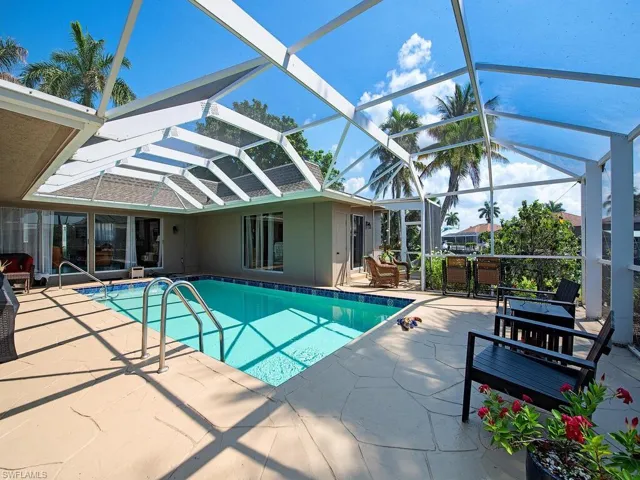 View of pool with glass enclosure and a patio area