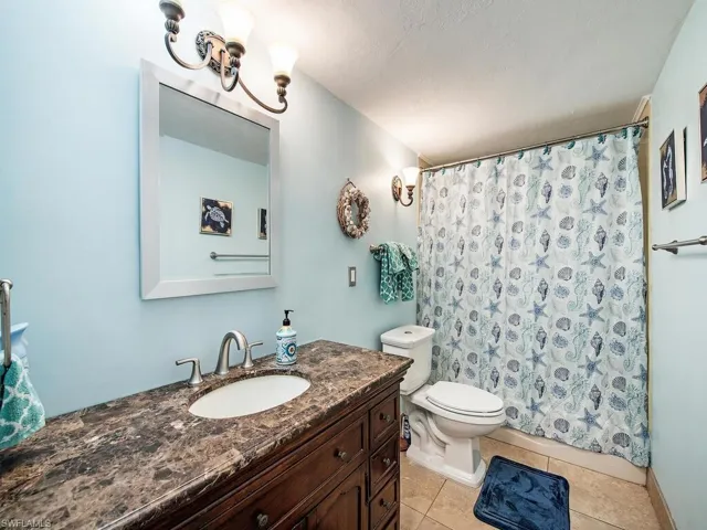 Bathroom with a notable chandelier, tile flooring, vanity, and toilet