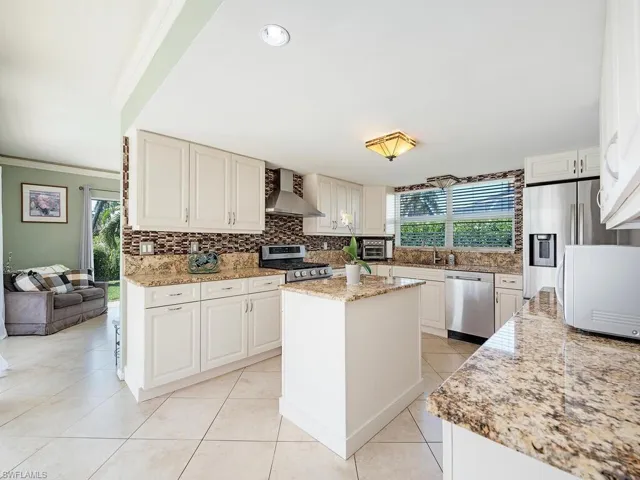 Kitchen featuring appliances with stainless steel finishes, a wealth of natural light, a center island, and wall chimney exhaust hood