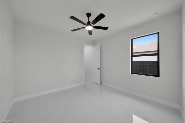 Empty room featuring light marble finish floors and ceiling fan