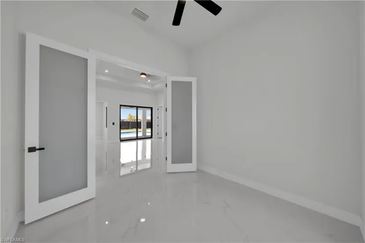 Spare room with light marble finish floors and ceiling fan