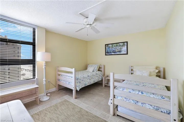 Bedroom with a ceiling fan, a textured ceiling, and tile patterned flooring