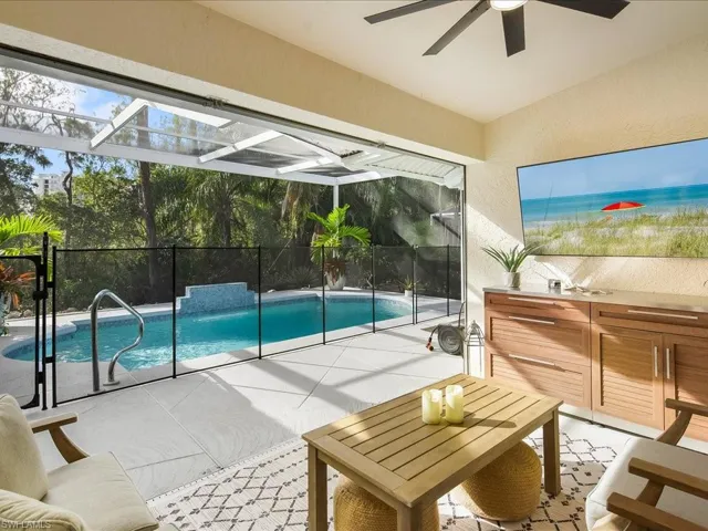 View of pool with glass enclosure, ceiling fan, and a patio area