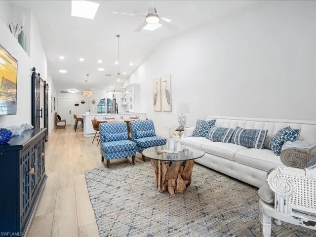 Living room featuring ceiling fan, light hardwood / wood-style flooring, and vaulted ceiling with skylight