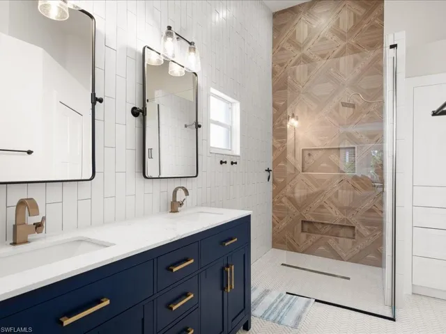Bathroom with tile patterned flooring, a shower, vanity, and tile walls