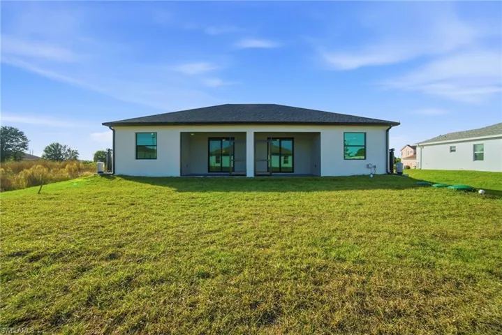 Back of property featuring a yard, a patio, and stucco siding