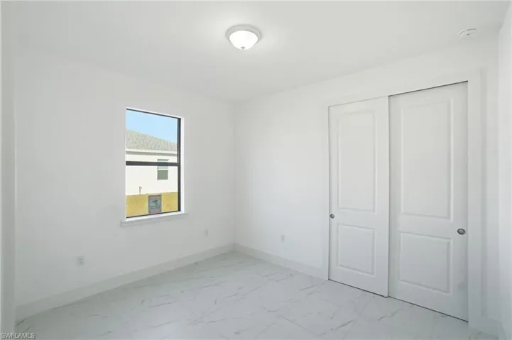 Unfurnished bedroom with light marble finish flooring and a closet
