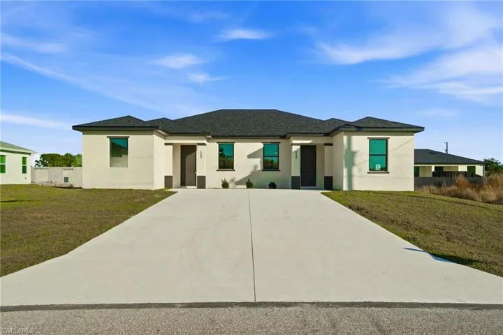 Prairie-style home with a front lawn, stucco siding, and driveway