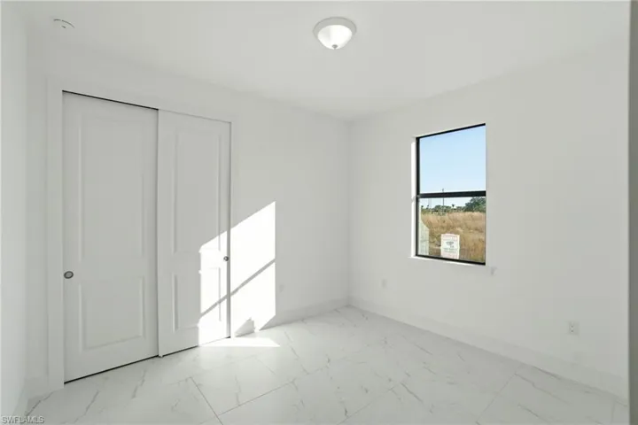 Unfurnished bedroom featuring light marble finish flooring and a closet