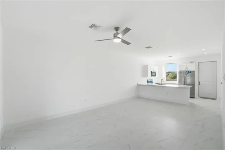 Unfurnished living room with light marble finish floors, ceiling fan, and recessed lighting