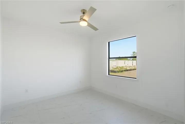 Empty room featuring a ceiling fan and light marble finish floors