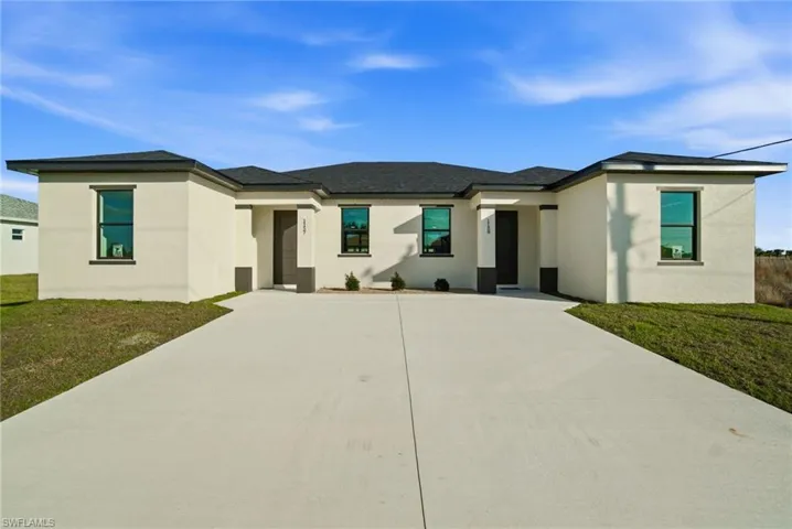Prairie-style home featuring a front yard, stucco siding, concrete driveway, and a shingled roof