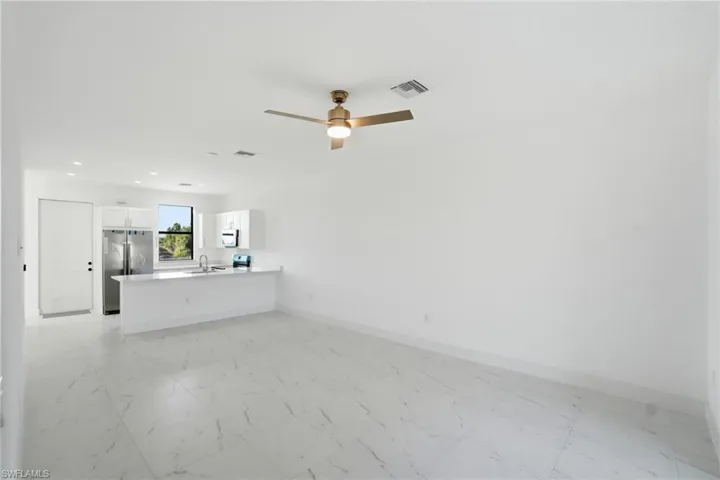 Unfurnished living room with light marble finish floors, a ceiling fan, and recessed lighting