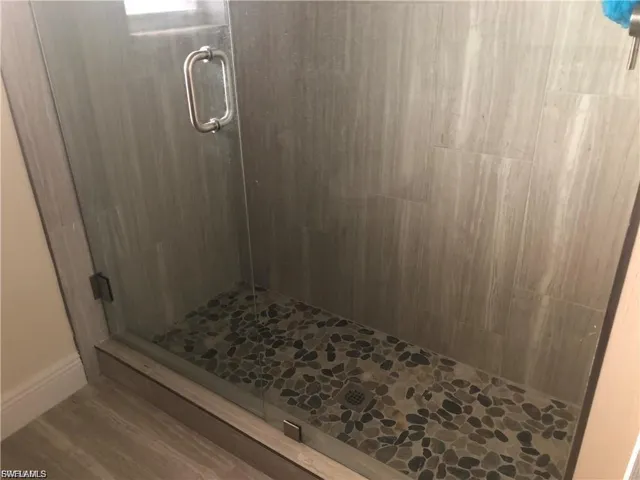 Bathroom featuring a shower stall and wood finished floors