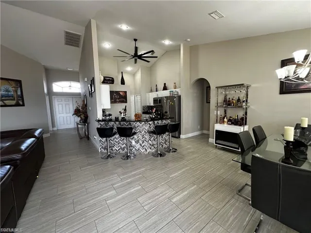 Living area featuring high vaulted ceiling, arched walkways, wood tiled floors, and ceiling fan
