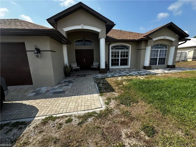 Entrance to property with stucco siding, a shingled roof, and a garage