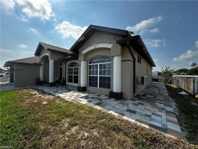 View of home's exterior featuring stucco siding, roof with shingles, and a patio area