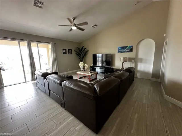 Living area with wood finish floors, a ceiling fan, and high vaulted ceiling