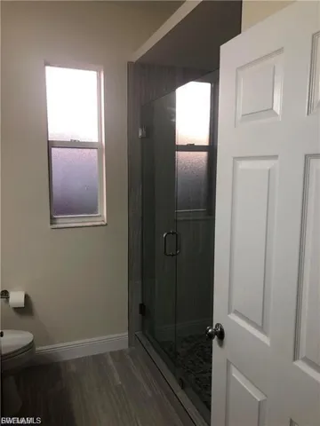 Full bath with a shower stall and dark wood-style floors