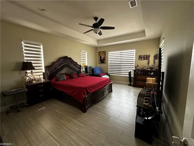 Bedroom with a tray ceiling, ceiling fan, and wood finish floors