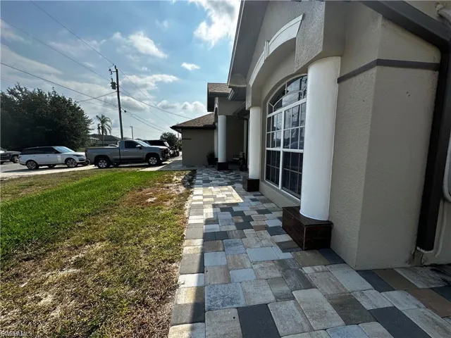 View of side of home with stucco siding, a yard, and a shingled roof