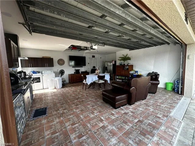 Garage featuring a textured wall, washing machine and dryer, and stainless steel fridge with ice dispenser