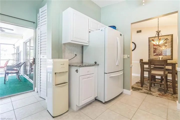 Kitchen featuring white cabinetry, light tile patterned floors, decorative light fixtures, and white refrigerator