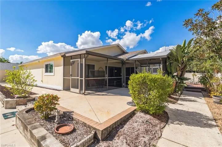 Back of property with a sunroom and a patio area