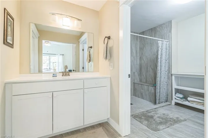 Bathroom with walk in shower, vanity, hardwood / wood-style floors, and ceiling fan