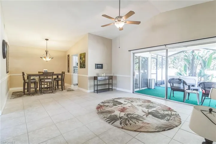 Living room featuring lofted ceiling, light tile patterned floors, and ceiling fan