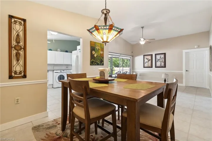 Tiled dining room with washer / dryer, ceiling fan, and lofted ceiling