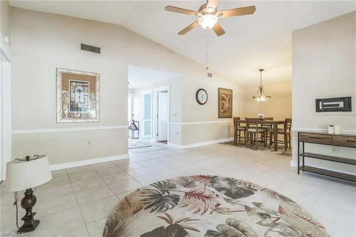 Living room featuring lofted ceiling, light tile patterned floors, and ceiling fan