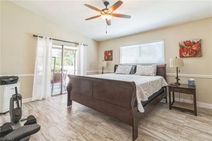 Bedroom with access to exterior, multiple windows, ceiling fan, and vaulted ceiling