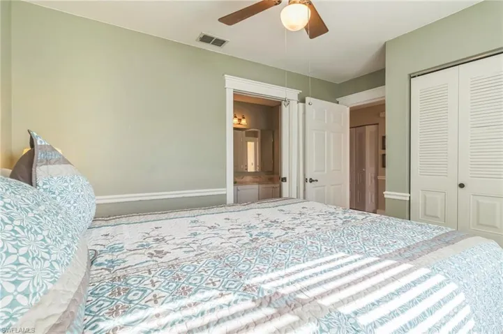 Bedroom with ensuite bathroom, ceiling fan, and a closet