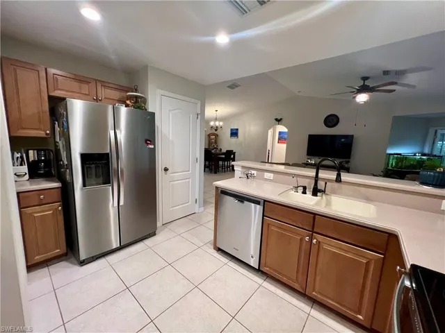 Kitchen with ceiling fan with sink, light tile patterned floors, and stainless steel appliances