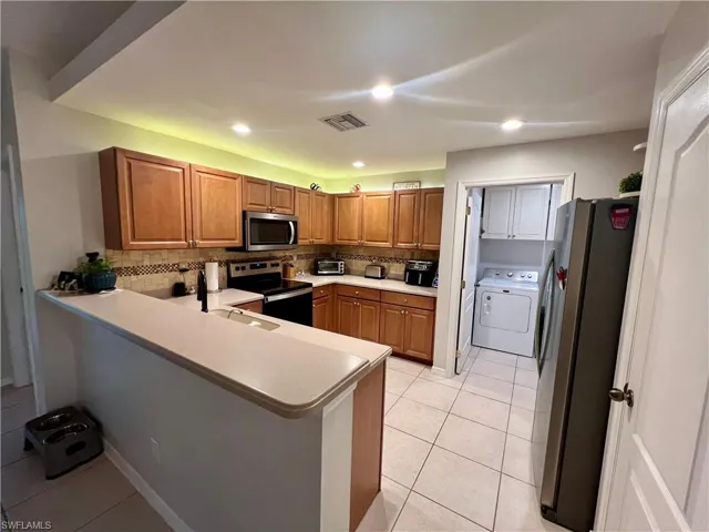 Kitchen featuring appliances with stainless steel finishes, decorative stone tile backsplash.