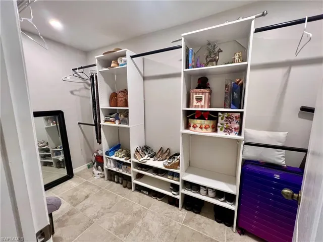 View of spacious walk in closet with built in closet shelving.