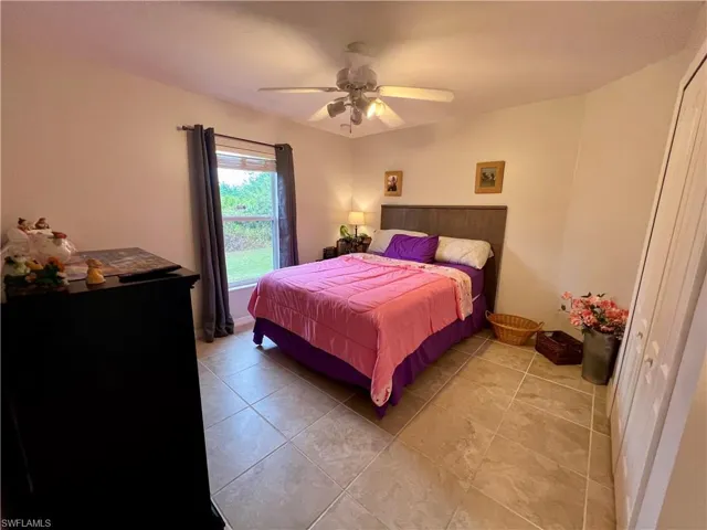 Tiled bedroom with ceiling fan and a closet