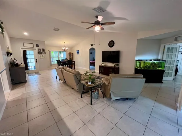 Tiled living room with ceiling fan and cathedral ceilings.