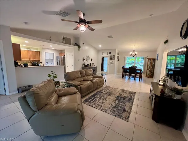 Tiled living room with ceiling fan and high cathedral ceilings.